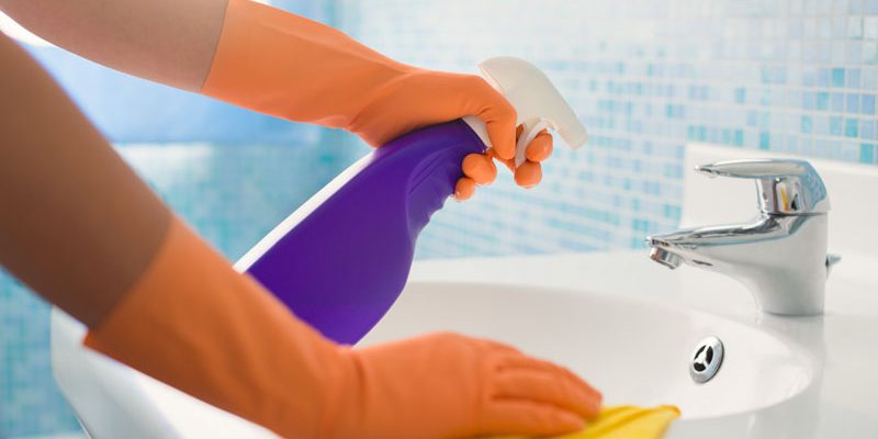 woman doing chores cleaning bathroom at home